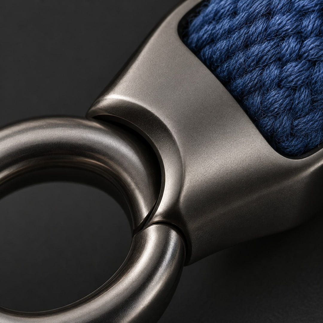 Macro detail of the Zinc Alloy Carabiner Keychain showing its smooth gunmetal finish and blue fabric texture.