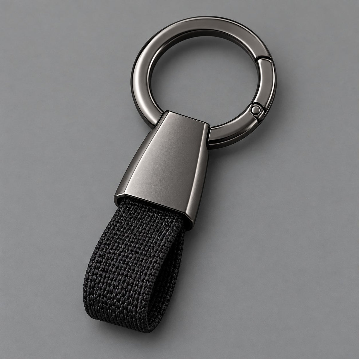 Black Zinc Alloy Carabiner Keychain with a gunmetal circular ring on a light charcoal studio background.