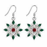 A matching pair of red and green accented snowflake stud earrings on a pure white background.