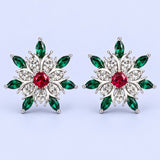 Silver snowflake stud earrings with red and green stones on a pale icy lavender backdrop.
