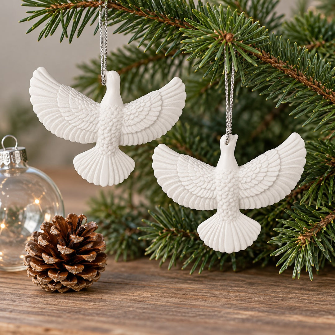 Two white acrylic dove ornaments sit beside a pinecone and glass bauble to show their compact scale.