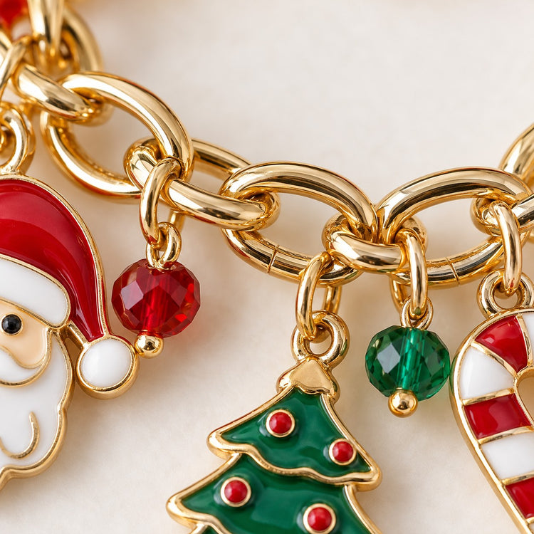 Macro detail of the Christmas charm bracelet showing smooth gold-tone links, glossy enamel and bead accents.