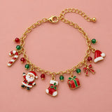 Gold Christmas charm bracelet with Santa, stocking, gift and candy cane charms on a soft blush studio backdrop.