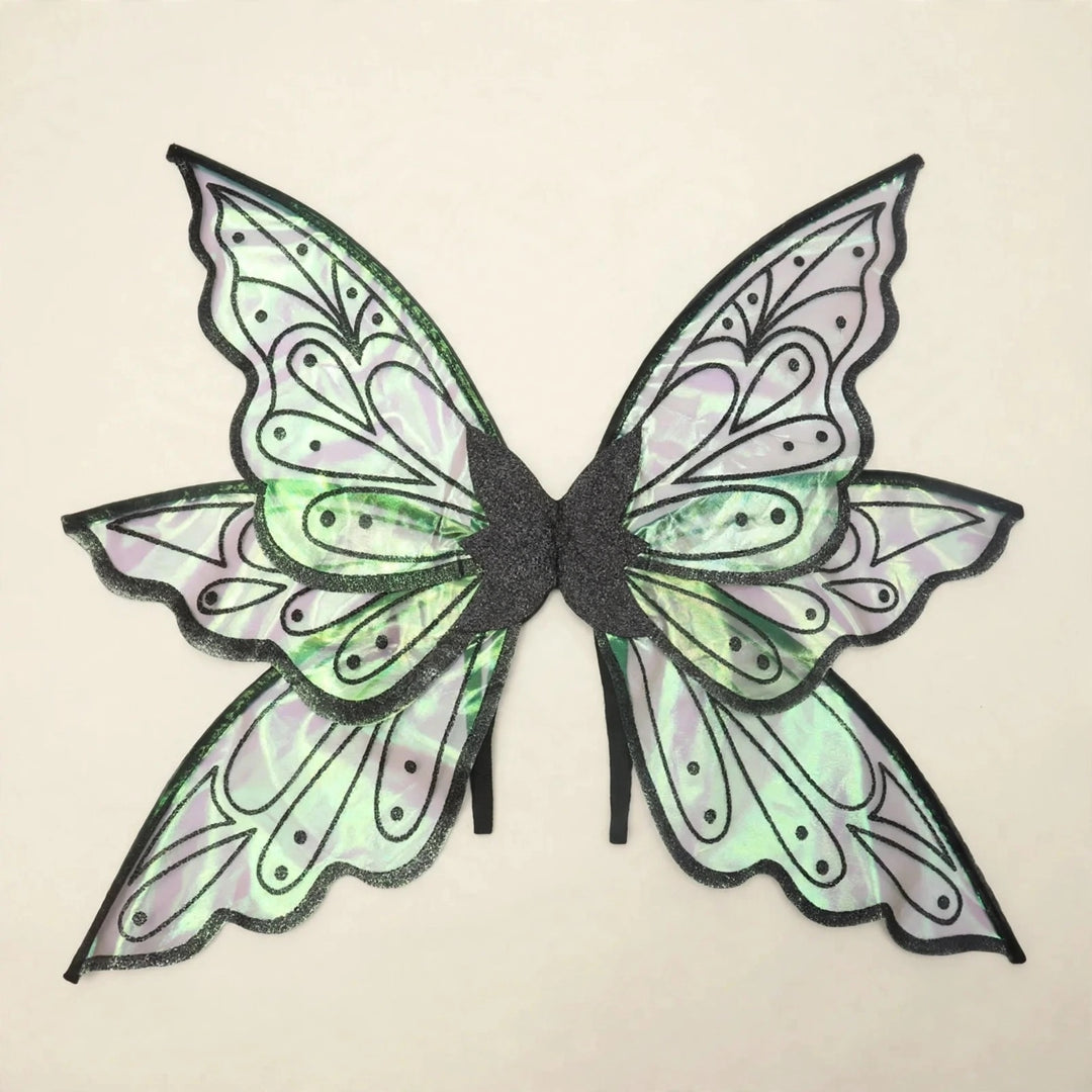 Iridescent fairy wings with black borders, dotted teardrop patterns, and pale green reflections rest against a cream background.
