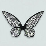 Fairy wings with black swirling outlines, translucent iridescent panels, and rounded lower sections rest against a light grey background.