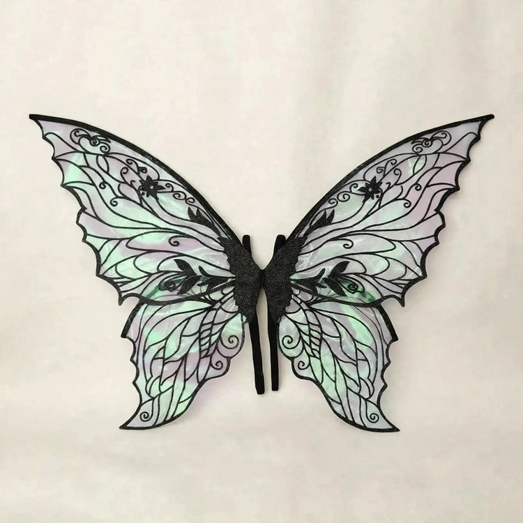 Fairy wings with black floral patterns, iridescent panels, and scalloped edges spread against a cream background.