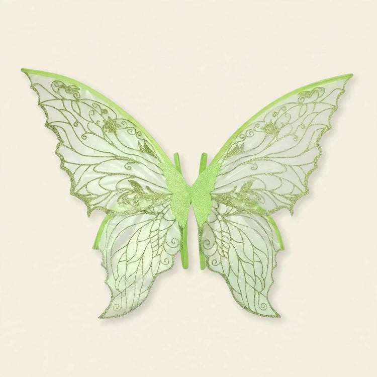 Pale green fairy wings feature translucent panels, glittery swirling patterns, scalloped edges, and central straps against a cream background.