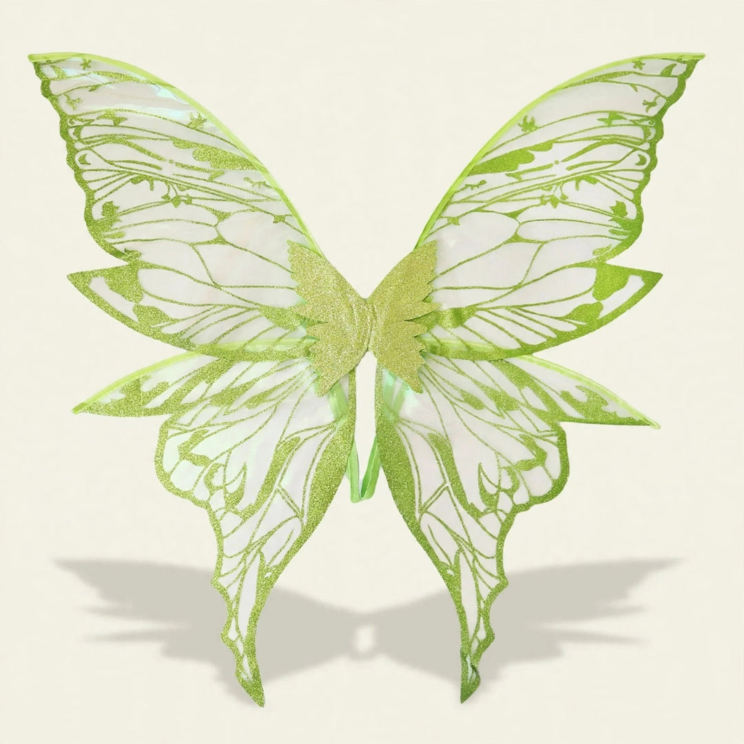Green fairy wings feature translucent panels, glittery outlines, and elongated lower tips, casting a shadow against a cream background.