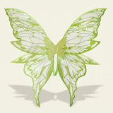 Green fairy wings feature translucent panels, glittery outlines, and elongated lower tips, casting a shadow against a cream background.