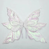 Iridescent fairy wings feature silver glitter borders, swirling patterns, and pink and green reflections against a pale gray background.