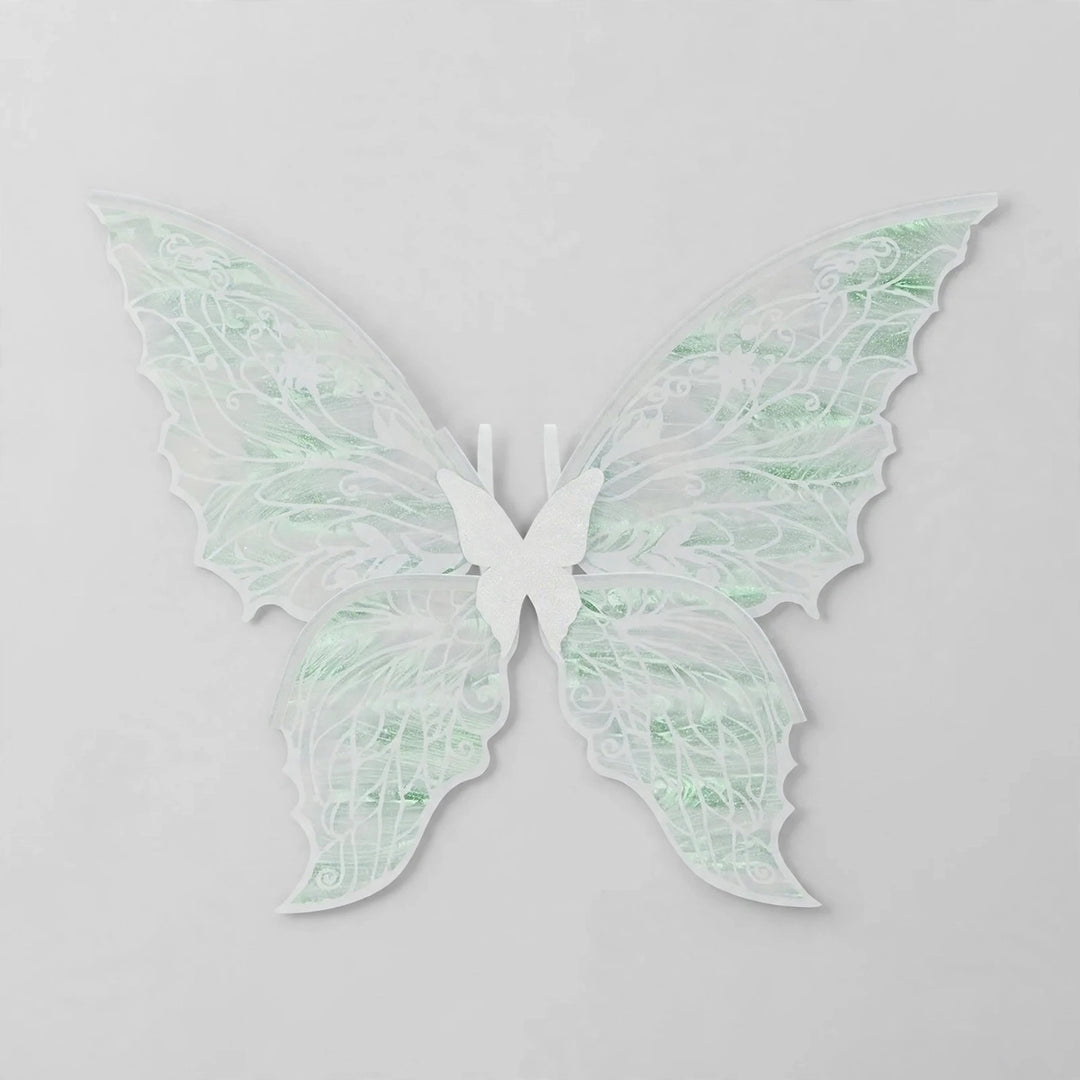 White fairy wings with translucent pale green reflections, delicate swirling patterns, and pointed lower tips rest against a light grey background.