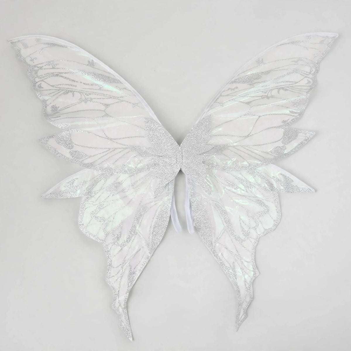 White iridescent fairy wings with glittery vein patterns and long curved lower tips spread against a light grey background.