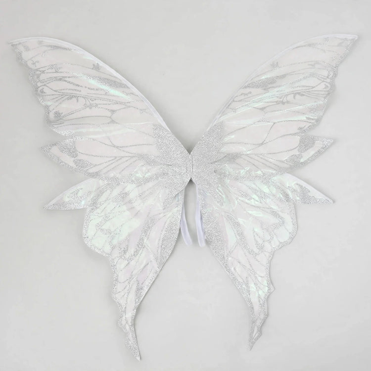 White iridescent fairy wings with glittery vein patterns and long curved lower tips spread against a light grey background.