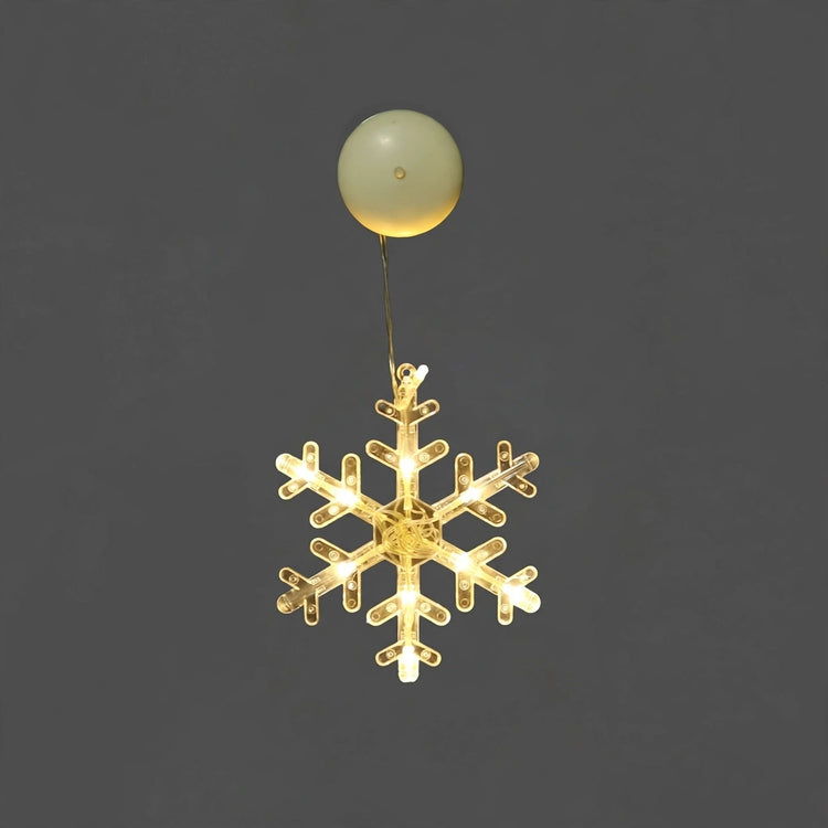 Clear snowflake-shaped lighted ornament with warm white lights hangs beneath a round cream suction cup against a plain gray background.
