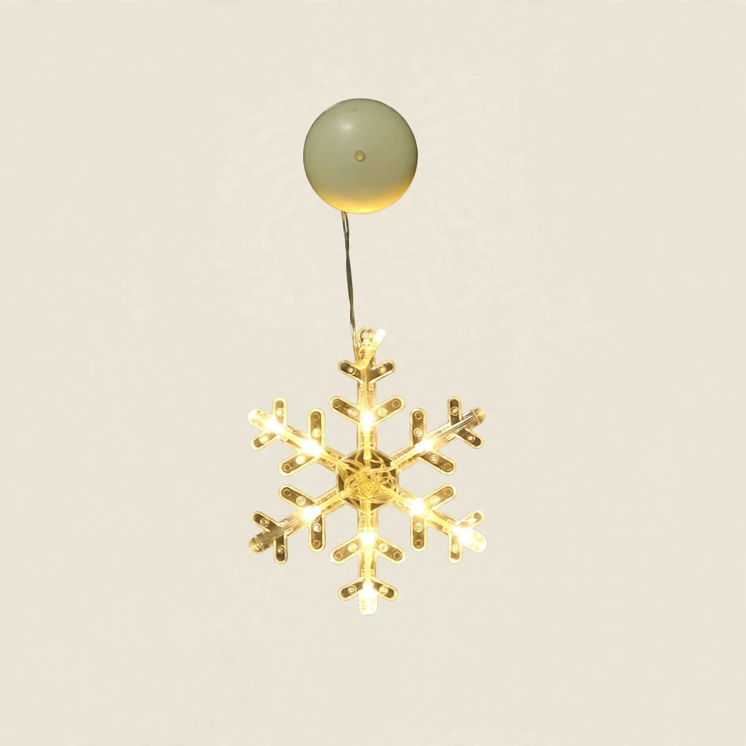 A clear six-pointed snowflake-shaped lighted ornament glows warm yellow beneath a round cream housing against an off-white background.