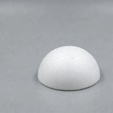 A white foam half ball with a lightly textured surface sits on its flat base against a plain gray background.