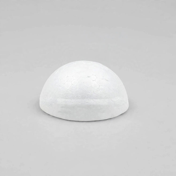 A white foam half ball sits centered on a light gray surface with ample empty space around it.