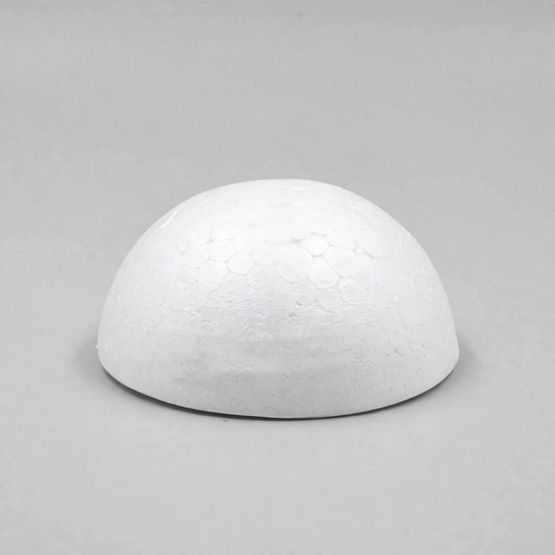 A white foam half ball with a textured curved surface rests on its flat base against a light gray background.