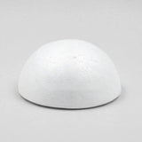 A white foam half ball rests flat-side down on a light gray surface, casting a narrow shadow beneath its edge.