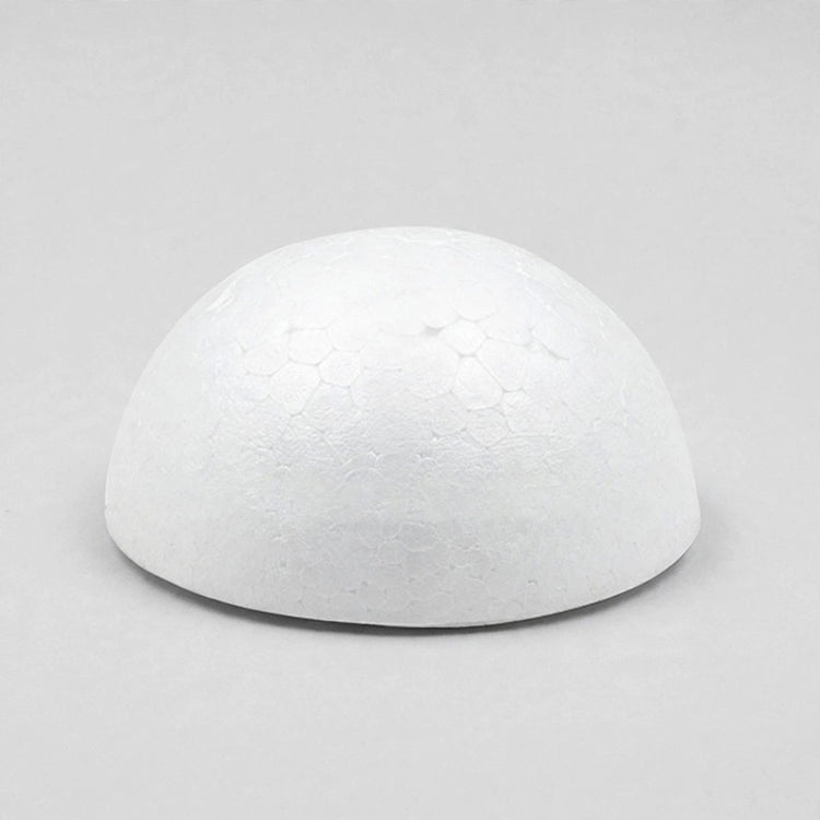 A white foam half ball rests flat-side down on a light gray surface, casting a narrow shadow beneath its edge.