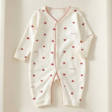 Cream long-sleeve baby romper with red hearts, Love lettering and red scalloped trim lies flat on a cream background.