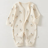 Cream ribbed baby romper with small dog prints and a partially open snap front lies flat on a white background.