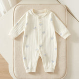 Cream ribbed baby romper with pale-blue motifs and cuffed sleeves and legs lies on a beige textured cushion.