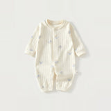 Cream long-sleeve baby romper with vertical fabric texture and small blue-hat dog motifs lies flat against a light background.