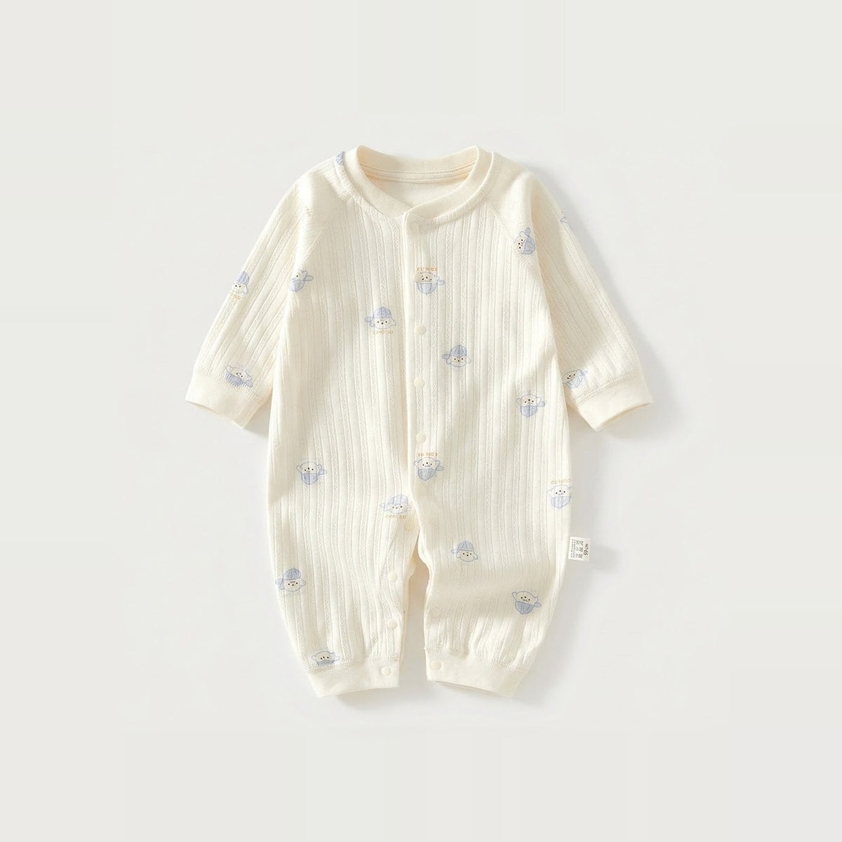 Cream long-sleeve baby romper with vertical fabric texture and small blue-hat dog motifs lies flat against a light background.