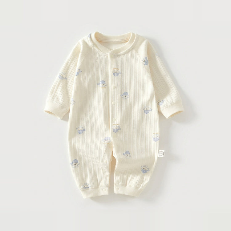 Cream textured baby romper with long sleeves, cuffed ankles, and small blue dog prints lies flat on a pale background.