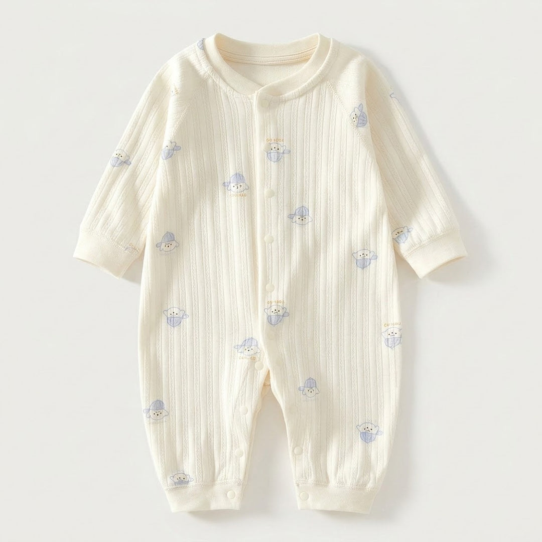 Cream textured long-sleeved baby romper with blue dog prints and front snap fasteners lies flat against a pale background.