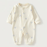 Cream textured long-sleeved baby romper with blue dog prints and front snap fasteners lies flat against a pale background.