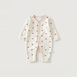 An off-white long-sleeve baby romper with a red heart pattern and red piping details, laid flat on a light gray background.