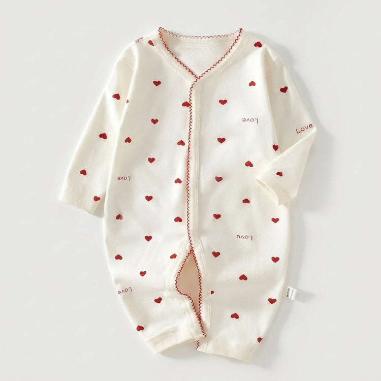 A baby long-sleeve footless romper in off-white, decorated with small red hearts and scattered 'Love' text, laid flat on a light gray background.