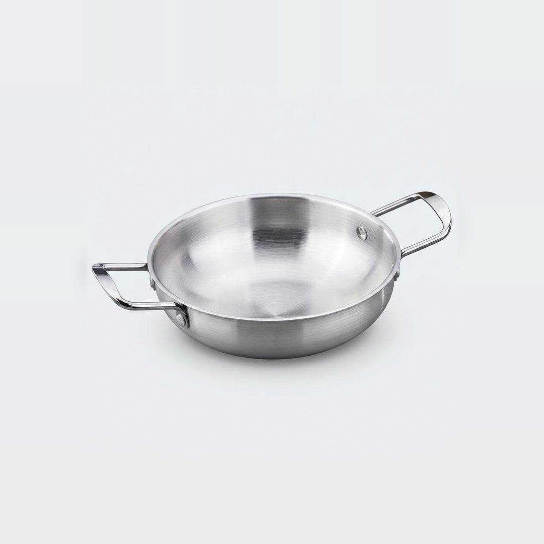 A silver stainless steel paella pan with two rectangular loop handles sits on a light gray background.