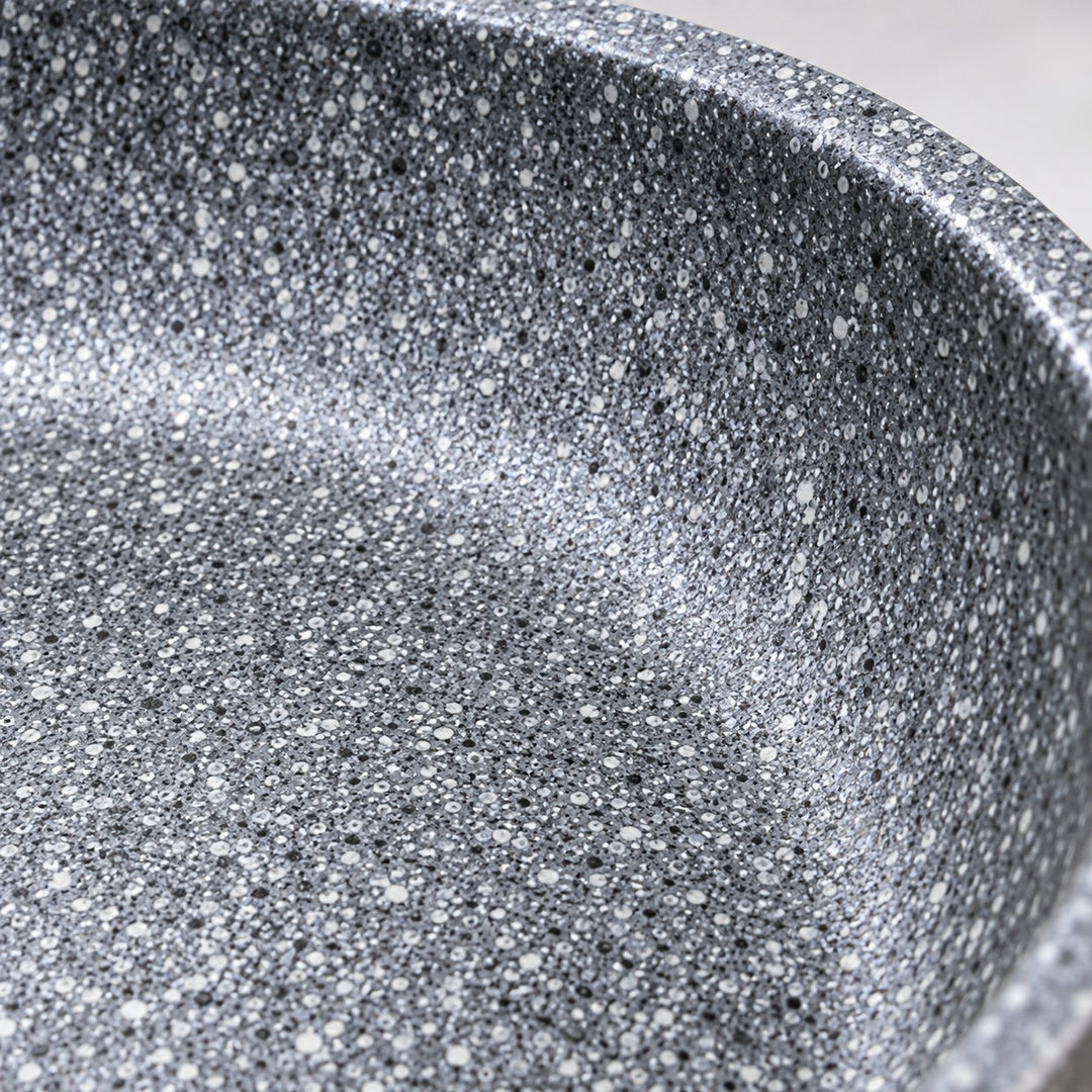 Macro detail of the smooth grey speckled non-stick cooking surface and curved pan rim.