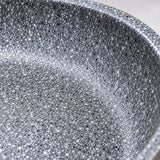 Macro detail of the smooth grey speckled non-stick cooking surface and curved pan rim.