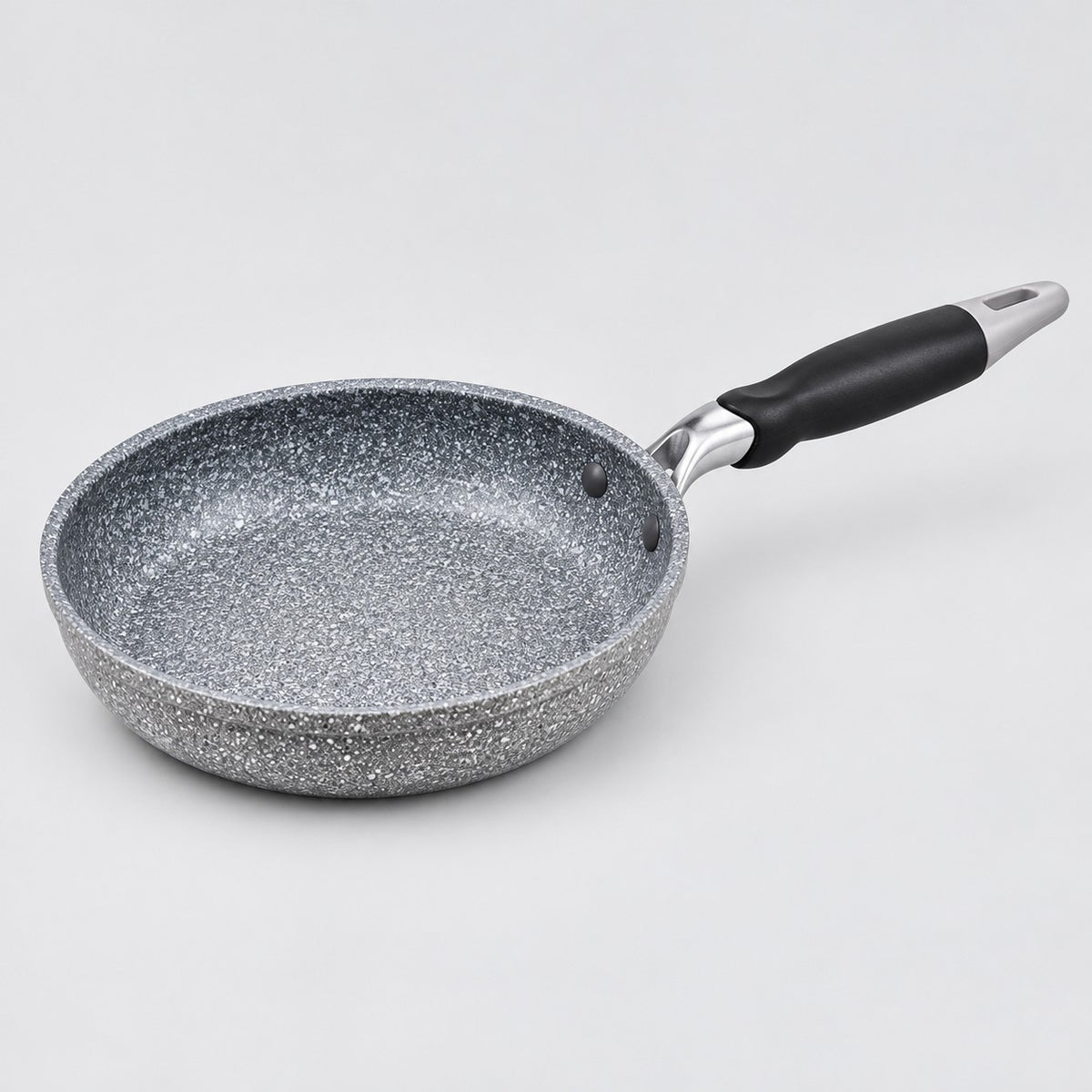 Grey speckled non-stick frying pan with a black handle shown alone against a pale studio background.