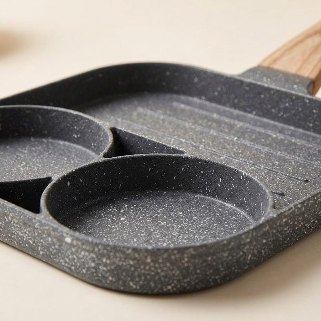 Close-up of a gray speckled egg frying pan showing two round wells and a ridged grill section on a cream surface.