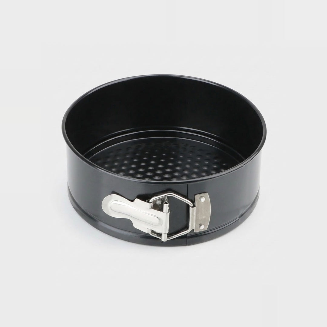 A black non-stick springform pan with a silver metal clasp and white release lever, shown on a light gray background.