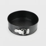 A black springform pan with a silver metal release clasp, shown from a top-down angle on a light gray background.