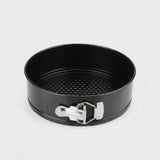 A black springform cake pan with a silver metal clasp, shown from a top-down angle on a light gray background.