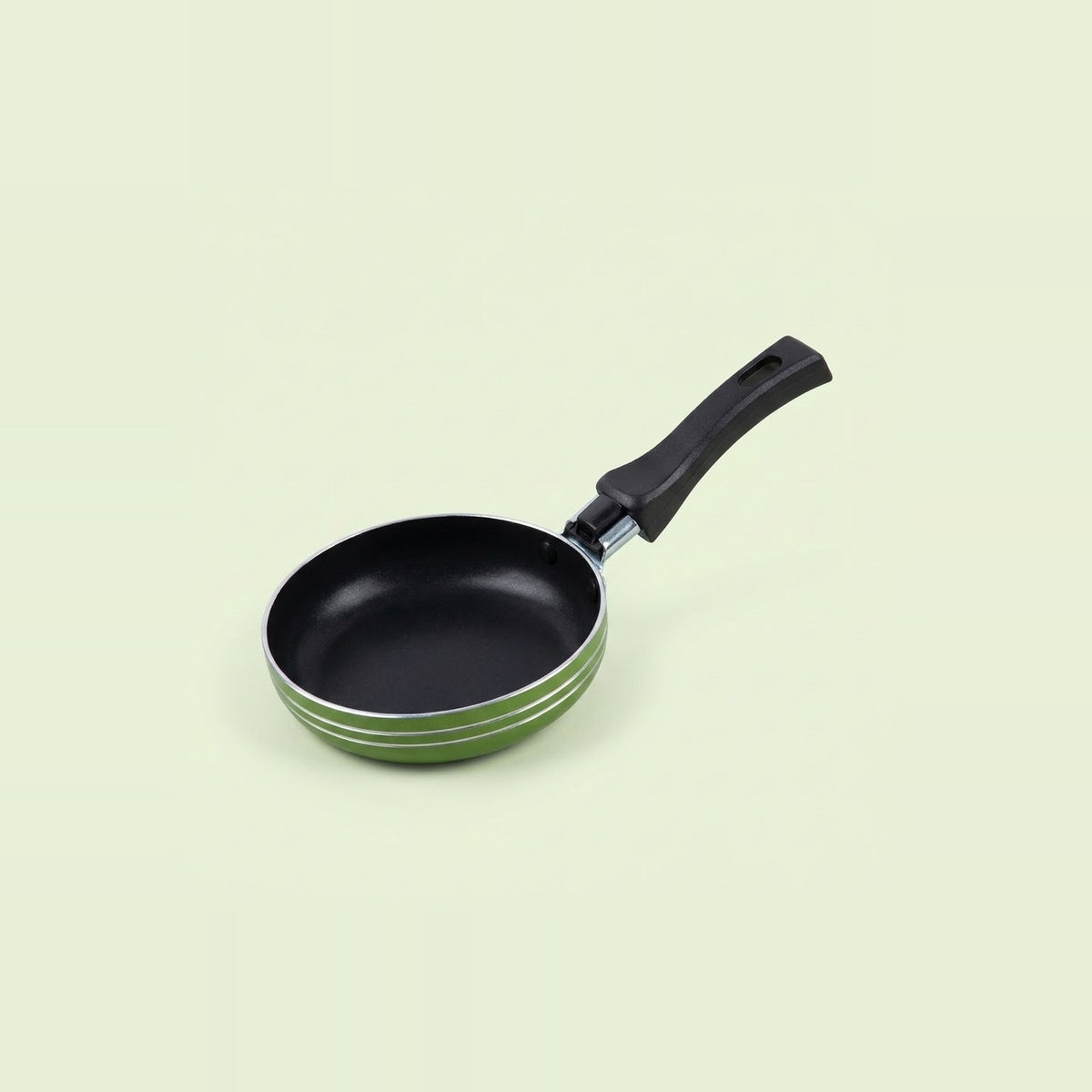 Green frying pan with a black nonstick interior, silver rim, and black hanging handle on a pale green background.
