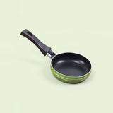 A small frying pan with a black non-stick interior, a black handle, and a green exterior accented with thin white stripes, shown on a pale green background.