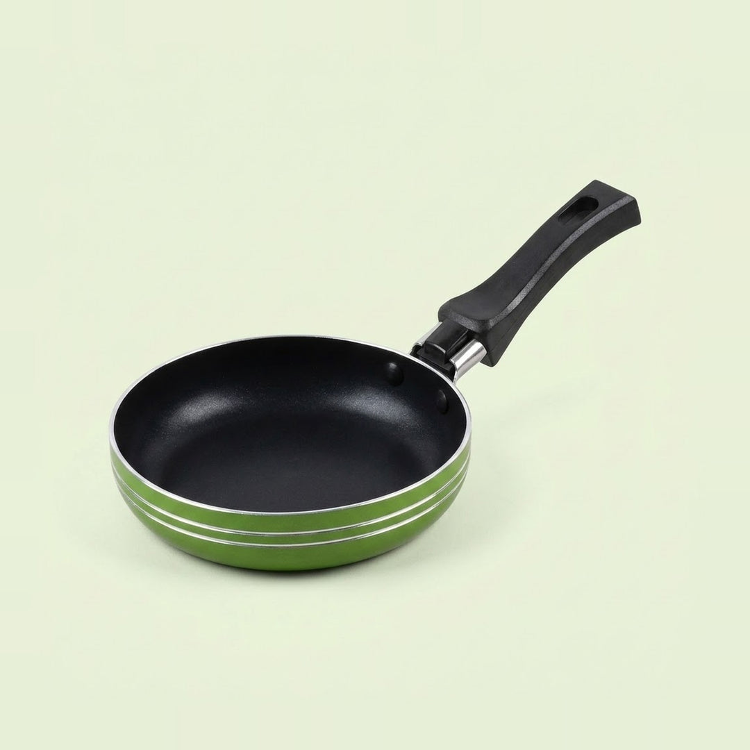 A small non-stick frying pan with a black interior, black handle, and a green exterior accented by two thin silver stripes, shown on a light cream background.