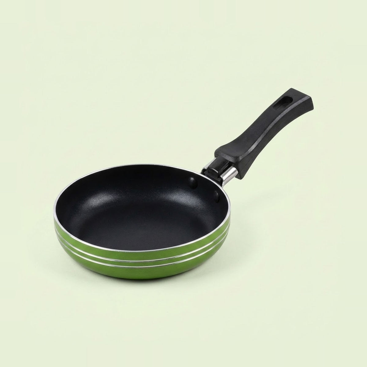 A small non-stick frying pan with a black interior, black handle, and a green exterior accented by two thin silver stripes, shown on a light cream background.