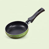 A small non-stick frying pan with a black interior, a dark brown handle, and a green exterior rim, shown on a solid pale green background.