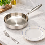 316 stainless steel frying pan beside a dinner plate and fork on a kitchen counter for scale.