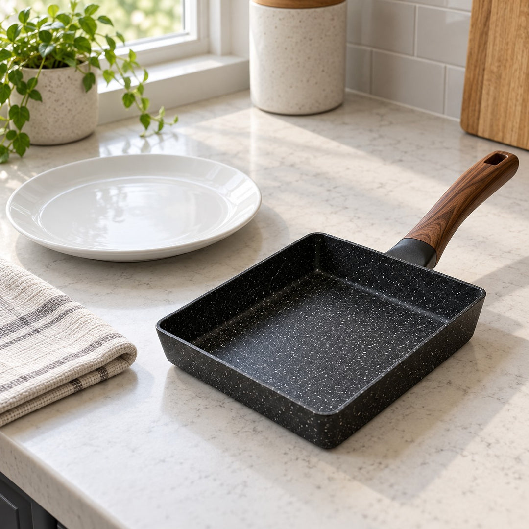 Compact Japanese omelet pan sits beside a breakfast plate to show its countertop scale.