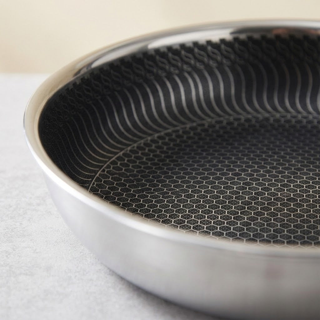 Close-up of a stainless steel frying pan showing the textured black non-stick interior with a honeycomb pattern and wavy ridge design.